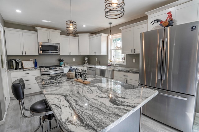 kitchen with a kitchen island, stainless steel appliances, light hardwood / wood-style floors, and sink