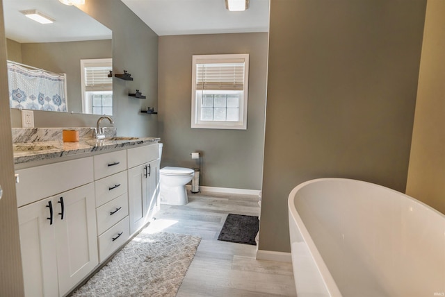 bathroom with a healthy amount of sunlight, toilet, wood-type flooring, and a washtub