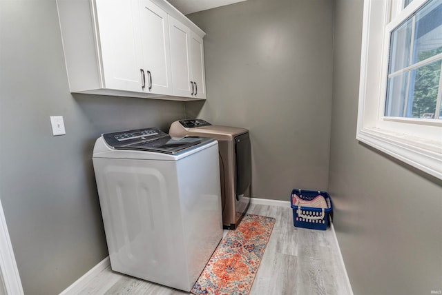 clothes washing area featuring cabinets, washer and dryer, and light hardwood / wood-style floors