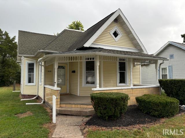 bungalow-style home with a porch, a front lawn, and a shingled roof