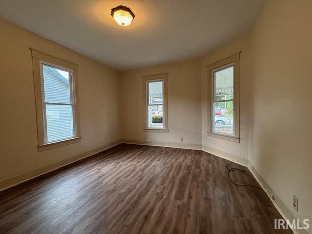 empty room with baseboards and dark wood finished floors