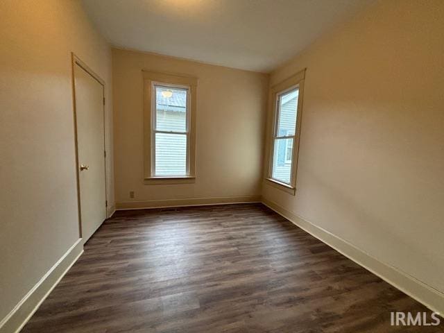 spare room with plenty of natural light, dark wood finished floors, and baseboards