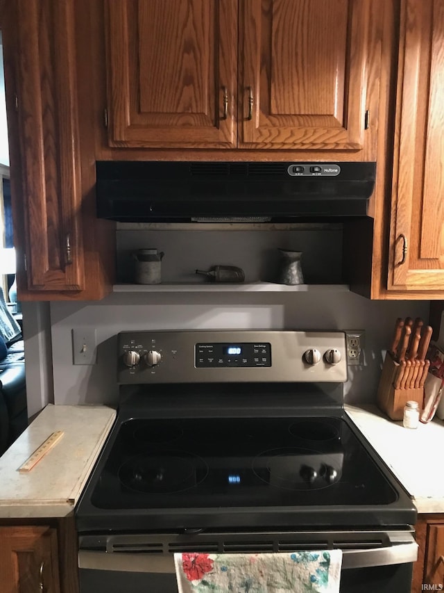 kitchen with light countertops, brown cabinetry, stainless steel electric range, and under cabinet range hood