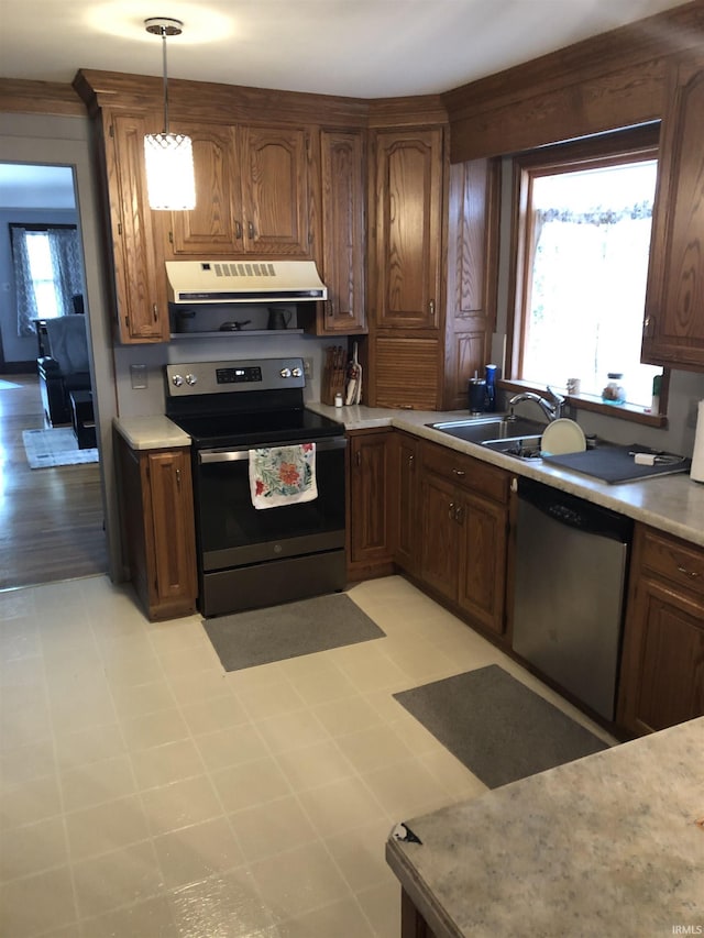 kitchen with appliances with stainless steel finishes, light countertops, a sink, and ventilation hood