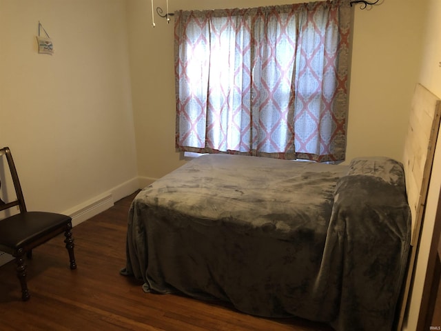 bedroom with dark wood-style floors, baseboard heating, and baseboards