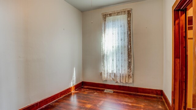 unfurnished room with plenty of natural light and dark wood-type flooring