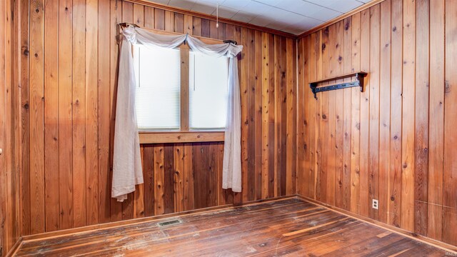 unfurnished room featuring wooden walls and dark hardwood / wood-style flooring