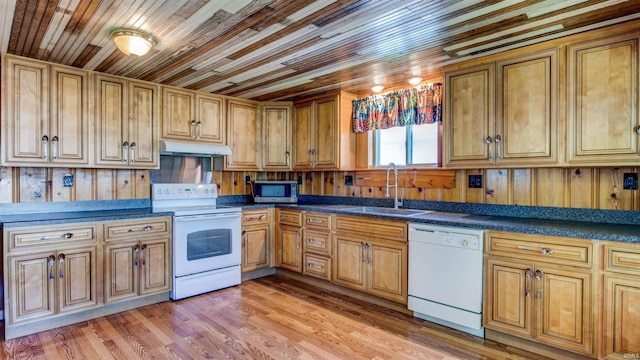 kitchen with light wood-type flooring, white appliances, wood walls, and sink