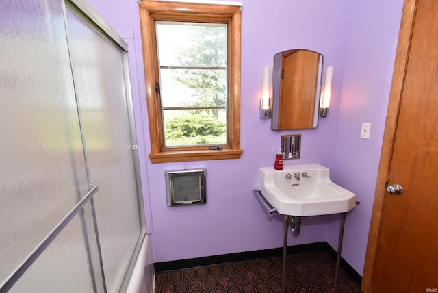 bathroom with tile patterned flooring, bath / shower combo with glass door, sink, and a healthy amount of sunlight