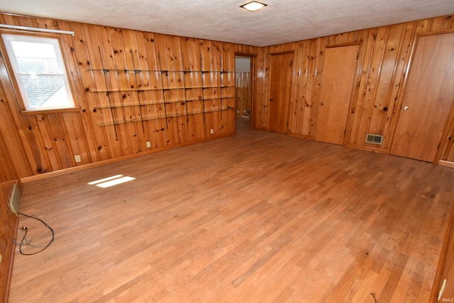 unfurnished room featuring wooden walls and light hardwood / wood-style flooring