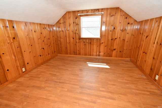 bonus room featuring lofted ceiling, light wood-type flooring, and wooden walls