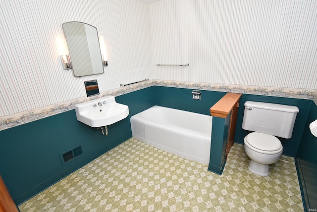 bathroom featuring toilet, a bathtub, sink, and tile patterned flooring