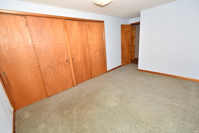 unfurnished bedroom featuring light colored carpet and a closet