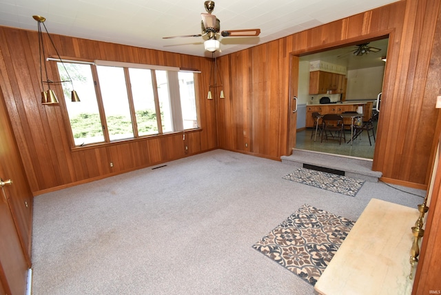 carpeted spare room featuring ceiling fan and wood walls