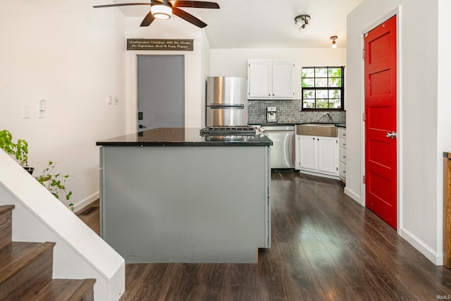 kitchen featuring appliances with stainless steel finishes, dark hardwood / wood-style flooring, white cabinetry, ceiling fan, and decorative backsplash