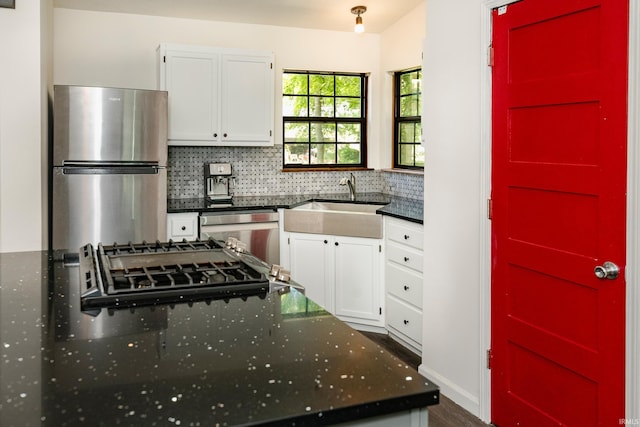 kitchen featuring white cabinets, appliances with stainless steel finishes, decorative backsplash, and sink