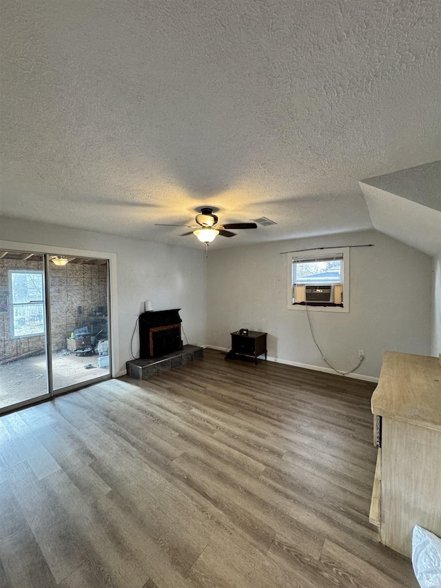 unfurnished living room with a wealth of natural light, cooling unit, a ceiling fan, and wood finished floors