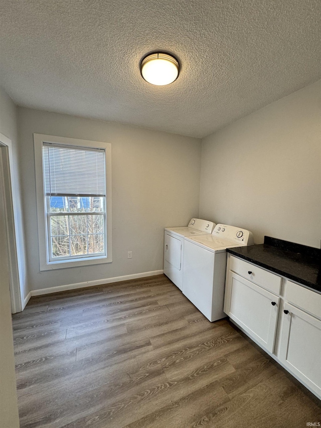 laundry room with a textured ceiling, dark wood-style flooring, baseboards, cabinet space, and washer and clothes dryer