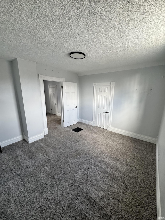 unfurnished bedroom featuring a textured ceiling, carpet floors, and baseboards