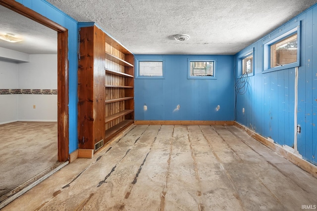 empty room featuring wood walls and a textured ceiling