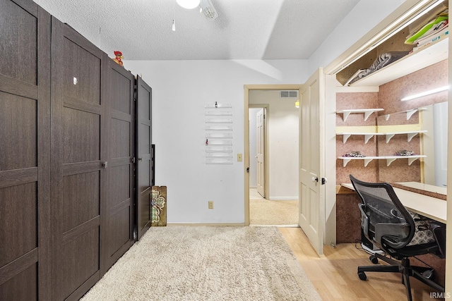 office featuring light wood-type flooring and a textured ceiling