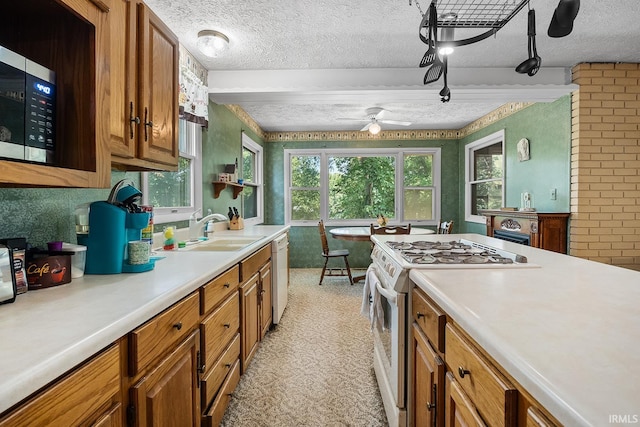 kitchen with white appliances, ceiling fan, sink, and a textured ceiling