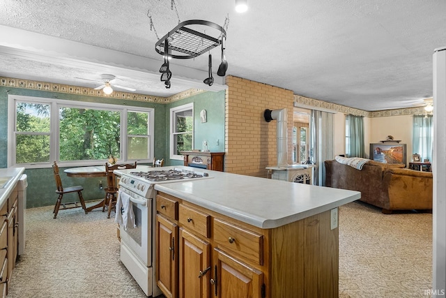 kitchen featuring light carpet, a textured ceiling, a center island, ceiling fan, and white gas stove