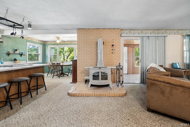 carpeted living room featuring a textured ceiling and a wood stove