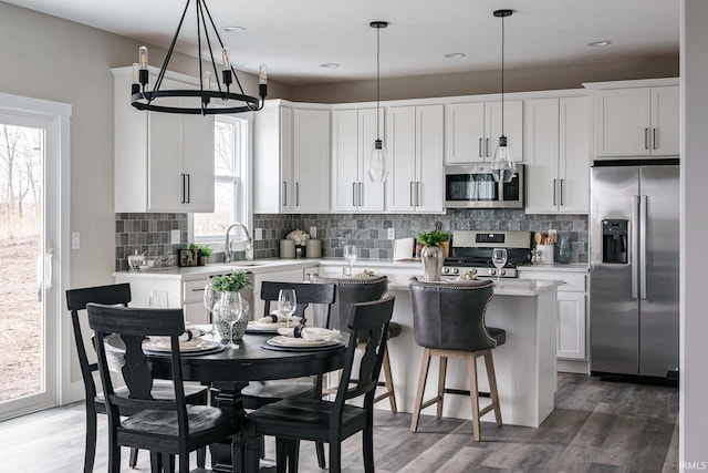 kitchen with a wealth of natural light, stainless steel appliances, hardwood / wood-style flooring, and tasteful backsplash