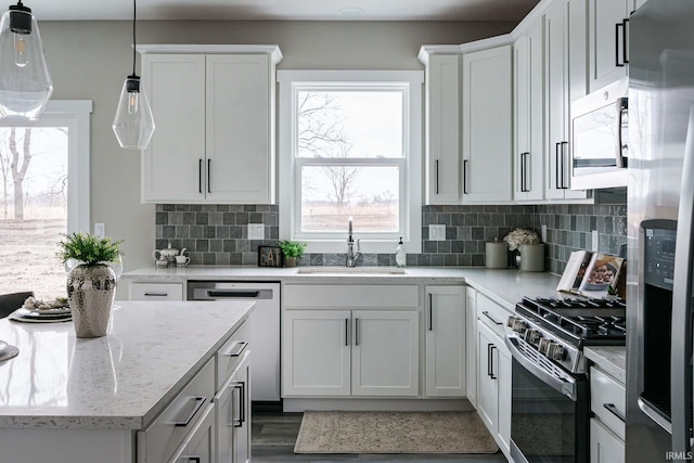 52520 E Trail Trail, South Bend, IN 46628 - kitchen with stainless steel appliances, a sink, tasteful backsplash, and hanging light fixtures