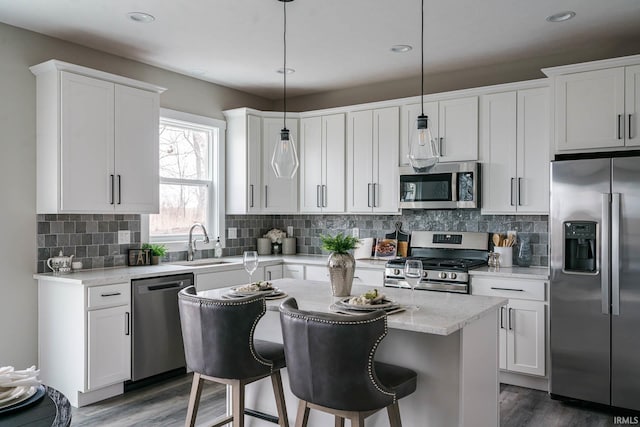 kitchen featuring hanging light fixtures, dark wood-type flooring, appliances with stainless steel finishes, and decorative backsplash