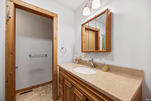 bathroom featuring stone finish floor, visible vents, vanity, and baseboards