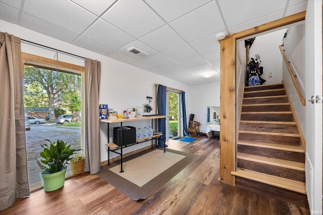 interior space with a drop ceiling, wood finished floors, visible vents, and baseboards