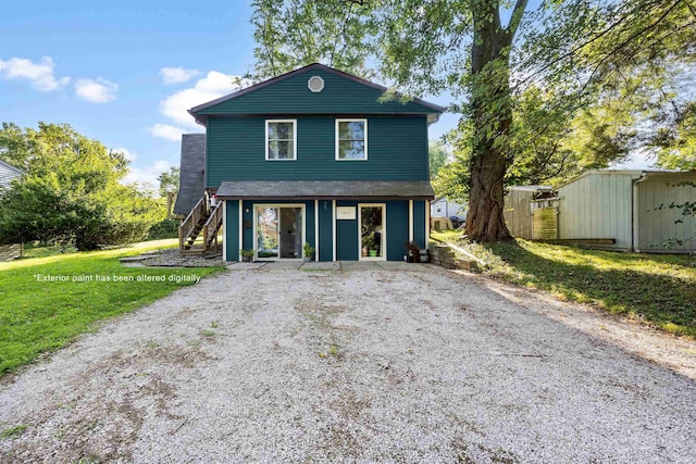 view of front of home with an outdoor structure, driveway, a front lawn, and stairs