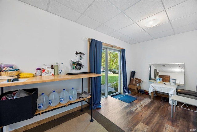 interior space with a paneled ceiling, baseboards, and wood finished floors