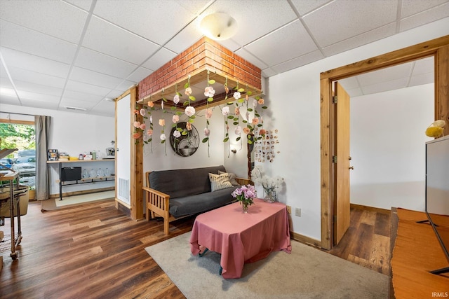 interior space with a drop ceiling, wood finished floors, and baseboards