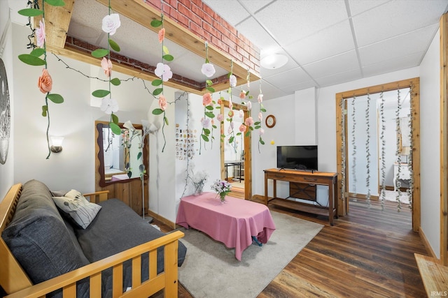 living area with a drop ceiling, baseboards, and wood finished floors