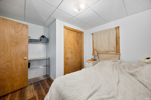 bedroom with a drop ceiling and wood finished floors