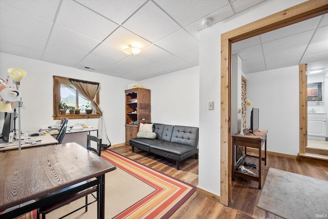 office with visible vents, a sink, wood finished floors, a drop ceiling, and baseboards