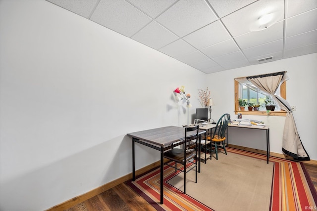 office area with baseboards, visible vents, a drop ceiling, and wood finished floors