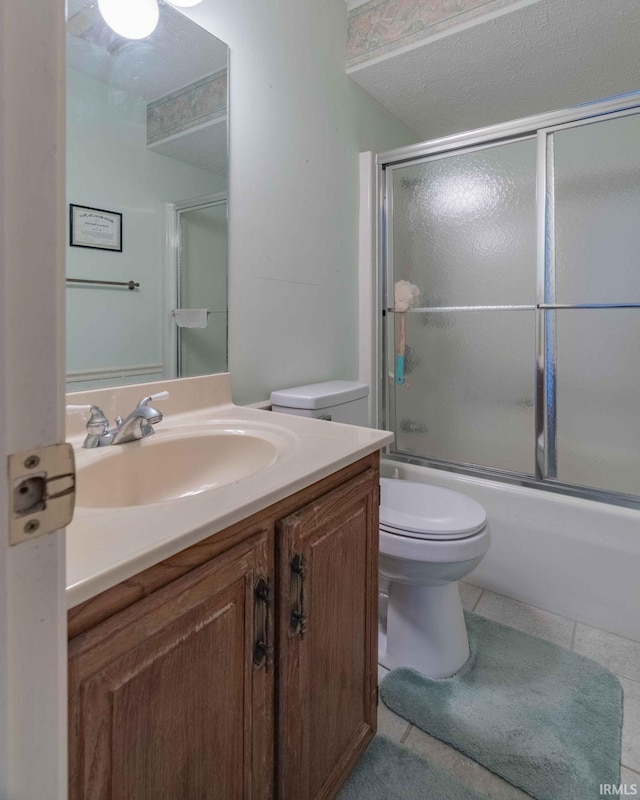 full bathroom featuring shower / bath combination with glass door, vanity, a textured ceiling, tile patterned flooring, and toilet