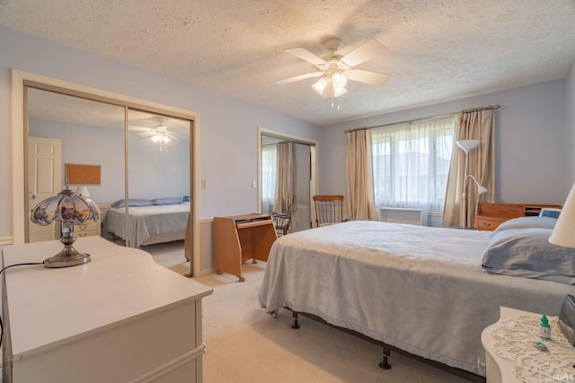 bedroom with a ceiling fan, a textured ceiling, and light colored carpet