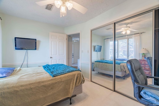 carpeted bedroom featuring a textured ceiling, ceiling fan, and a closet