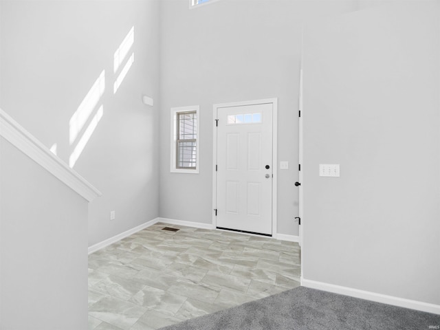 tiled foyer featuring a wealth of natural light and a high ceiling