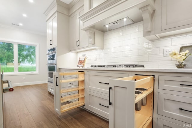 kitchen featuring dark hardwood / wood-style floors, premium range hood, tasteful backsplash, crown molding, and stainless steel appliances