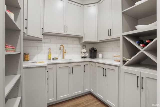 kitchen featuring white cabinets, backsplash, sink, and light hardwood / wood-style flooring