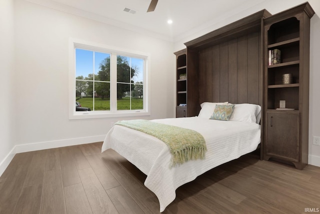 bedroom with ornamental molding, wood-type flooring, and ceiling fan