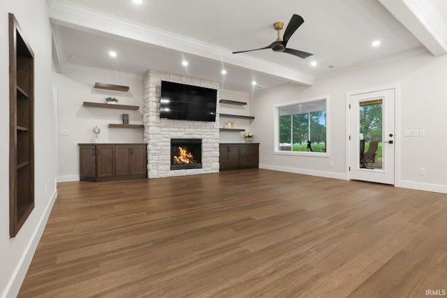 unfurnished living room with a fireplace, hardwood / wood-style floors, beam ceiling, ornamental molding, and ceiling fan