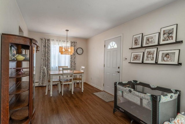 dining space featuring an inviting chandelier, baseboards, and dark wood finished floors