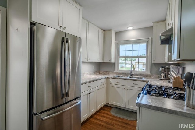 kitchen featuring dark wood-style floors, freestanding refrigerator, under cabinet range hood, white cabinetry, and a sink